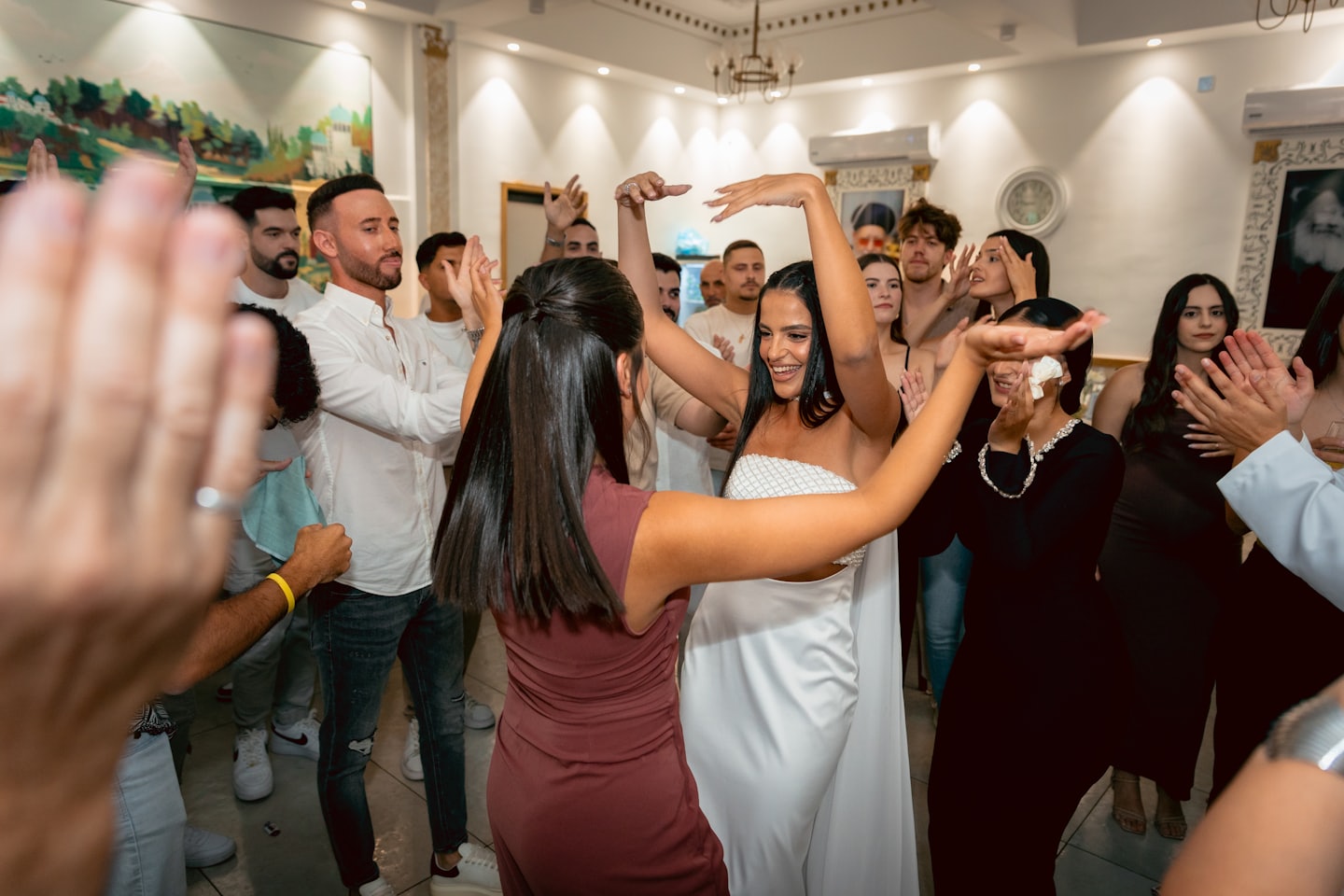 Zwei Frauen tanzen, während Freunde auf einer Party feiern.